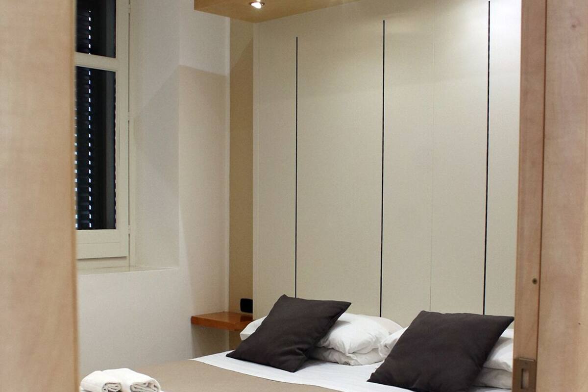 A bedroom with a bed, pillows, and neatly folded towels.