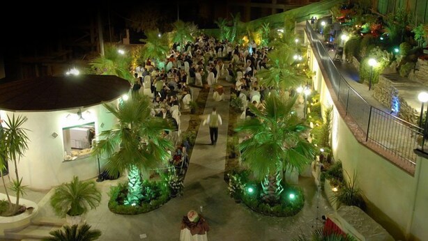 An indoor courtyard with palm trees and a crowd of people. - Leon d'Oro (Corleone)