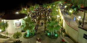 An indoor courtyard with palm trees and a crowd of people. - Leon d'Oro (Corleone)