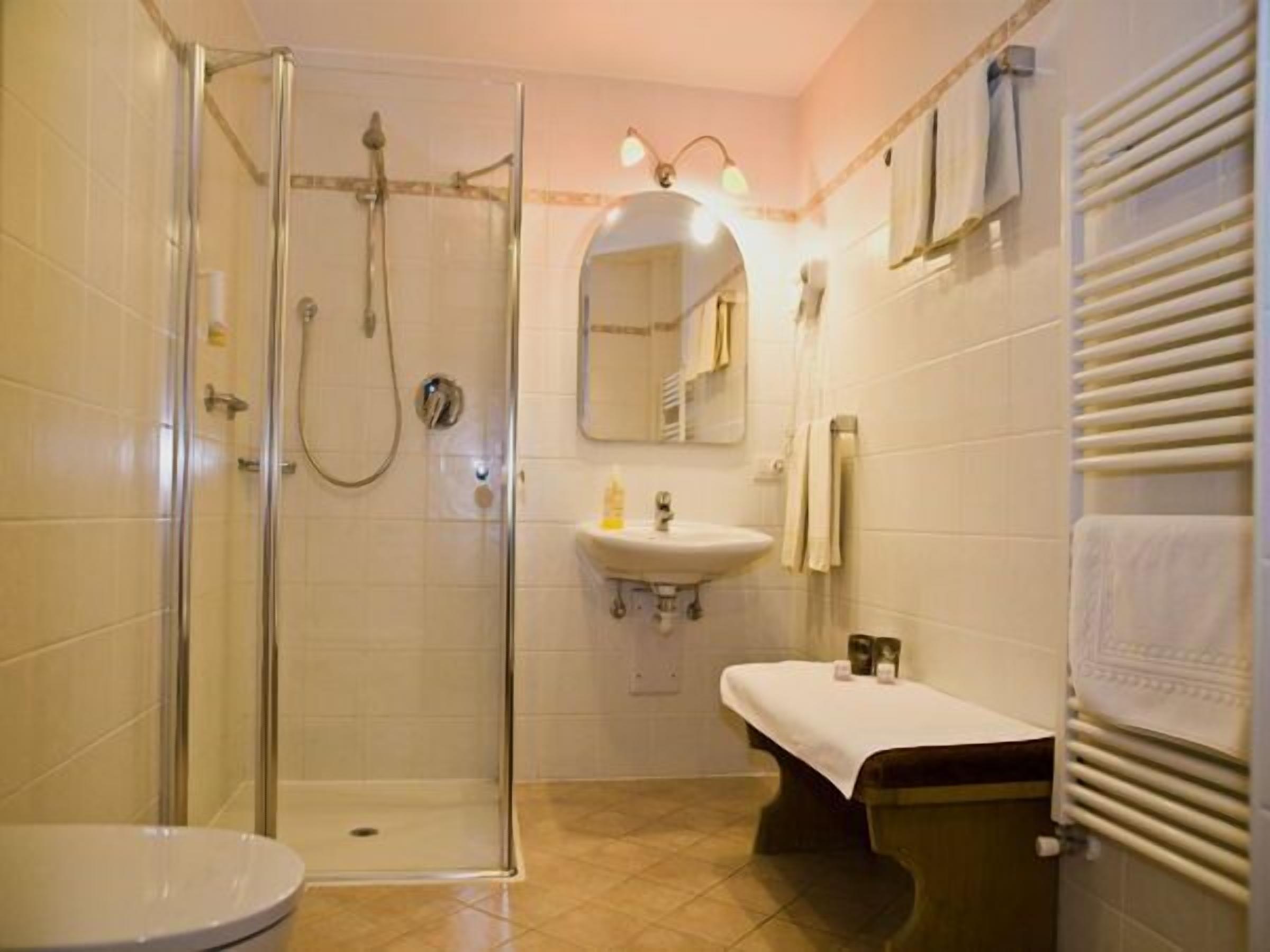 Un baño con ducha de vidrio, lavabo, inodoro y banco.