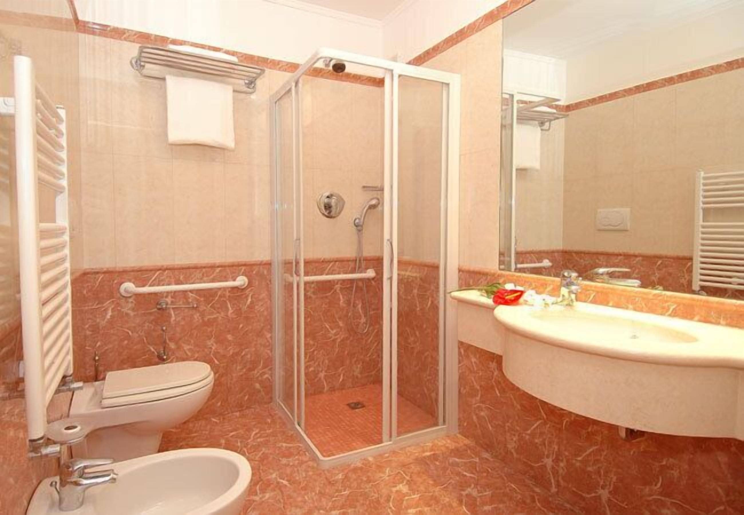 A bathroom with a glass-enclosed shower, a toilet, a sink, and a mirror.