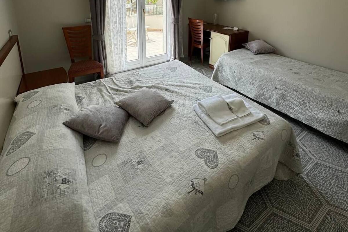 A hotel room with two beds, a TV, a desk, and a chair.