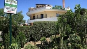 A hotel with a sign indicating it has a restaurant, piano bar, and pizza. - Leon d'Oro (Corleone)