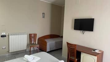 Ett hotellrum med en säng, ett skrivbord, en stol, en tv och ett element.