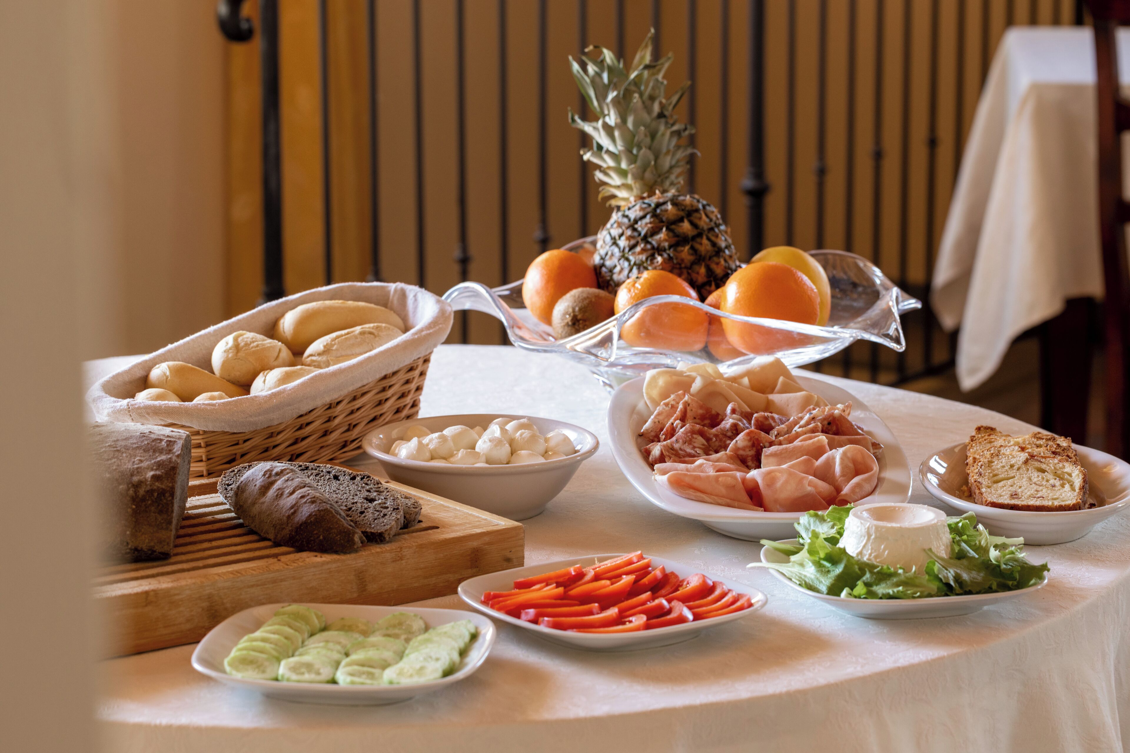 Una mesa con diversos alimentos, entre ellos pan, queso y frutas.