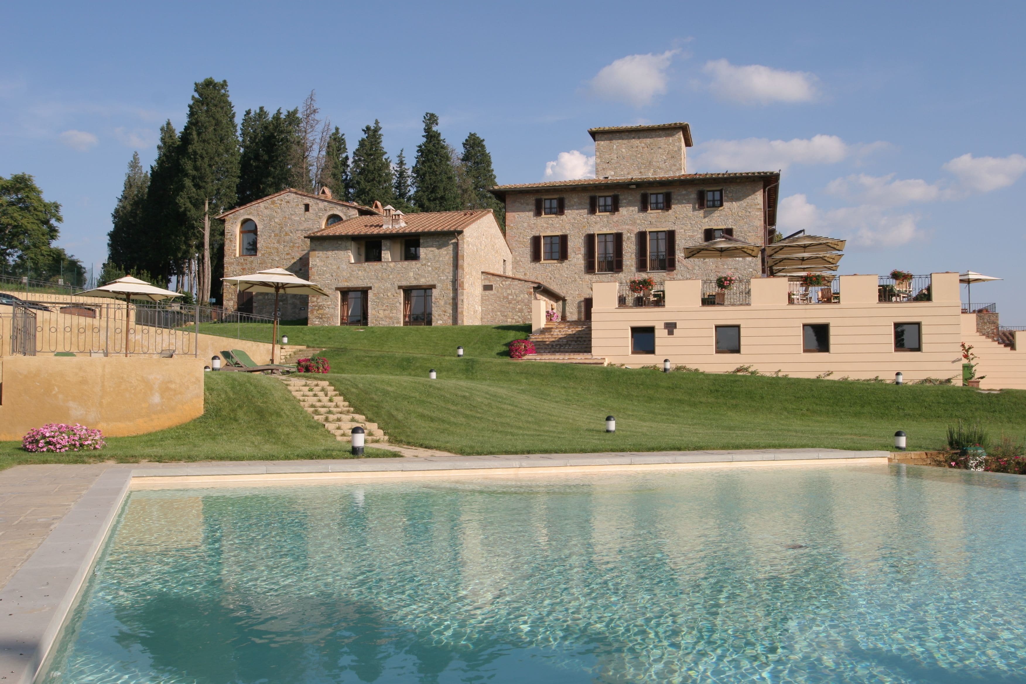 Una zona de piscina con un edificio de piedra al fondo.