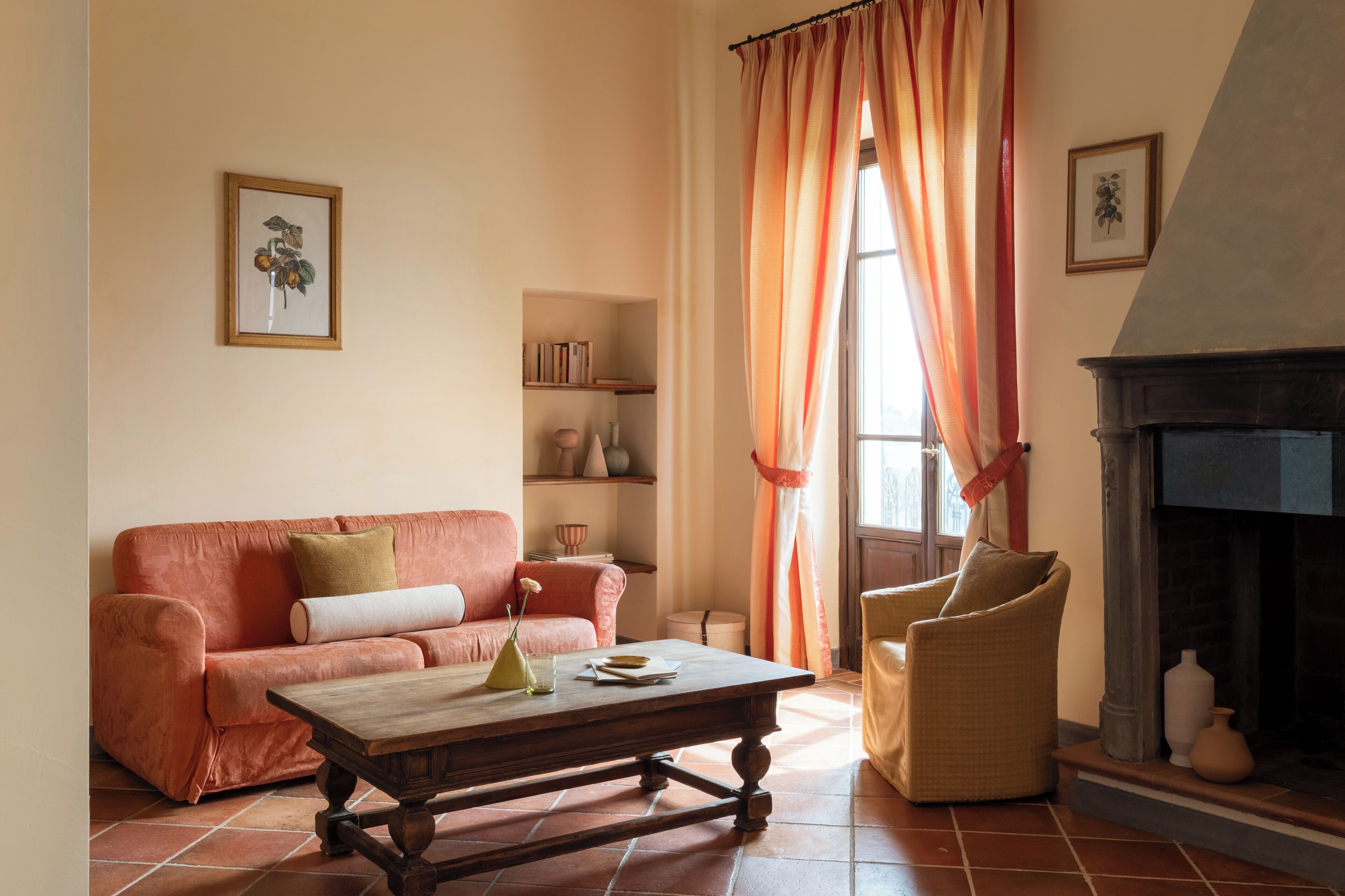 A living room with a sofa, armchair, fireplace, and a bookshelf.