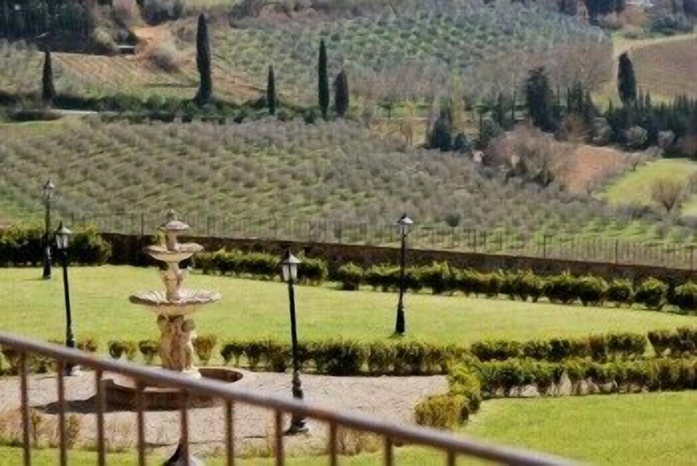 Un giardino curato con fontana, siepi potate e vista su dolci colline.
