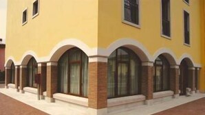 A yellow building with arched windows and a brick base. - Hotel Scaligero (Sommacampagna)
