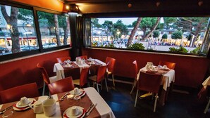 Ein Restaurant mit gedeckten Tischen, Blick auf die Straße und rotem Interieur.