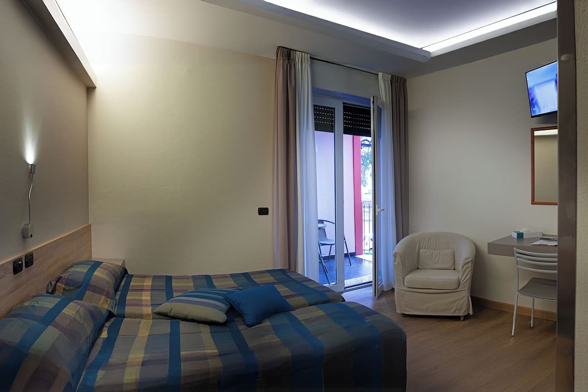 Een slaapkamer met een bed, een stoel, een bureau en een televisie.