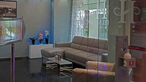 Ein moderner Empfangsbereich mit einer Rezeption, einer Couch und einem Glastisch.