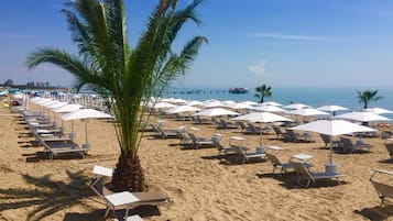 Nära stranden, vit sandstrand, solstolar och parasoller