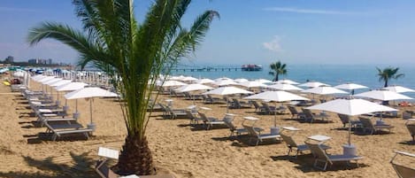 Una playa cerca, arena blanca, sillas reclinables de playa, sombrillas