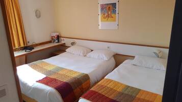 A hotel room with two beds, a desk with a telephone, and a painting on the wall.