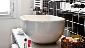 A bathroom with a large white vessel sink, a towel rack, a basket with toiletries, and a window. - Muà Boutique Bologna (Bologna)