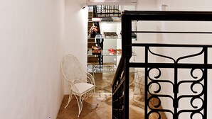 A staircase with a black railing, a white chair, and a flat-screen TV mounted above the stairs. - Muà Boutique Bologna (Bologna)