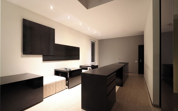 A modern, minimalist hotel room with a large bed, a desk, and a large window.
