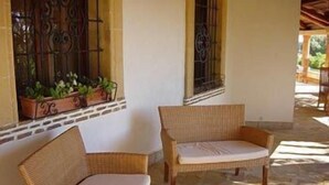 A room with wicker furniture, a small table, and a window with decorative iron bars. - A Giummara (Marsala)