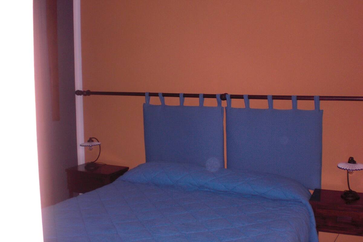 Un dormitorio con cama, mesita de noche y lámpara.