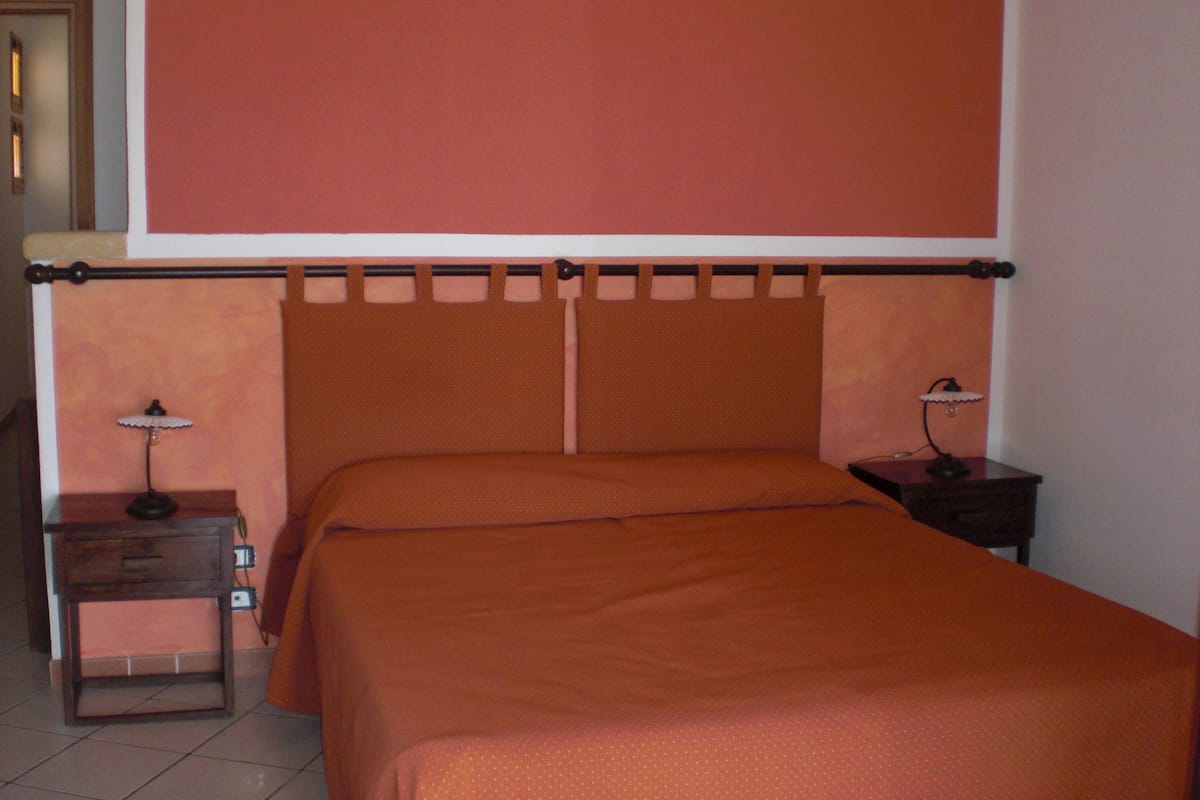 Un dormitorio con una cama, dos mesitas de noche y una mesita auxiliar.