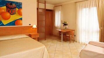 A hotel room with a bed, a desk, a chair, a wardrobe, and a painting on the wall.