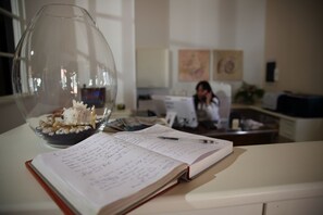 Ein Schreibtisch mit Notizbuch, Stift und einer dekorativen Glasvase mit Muscheln.