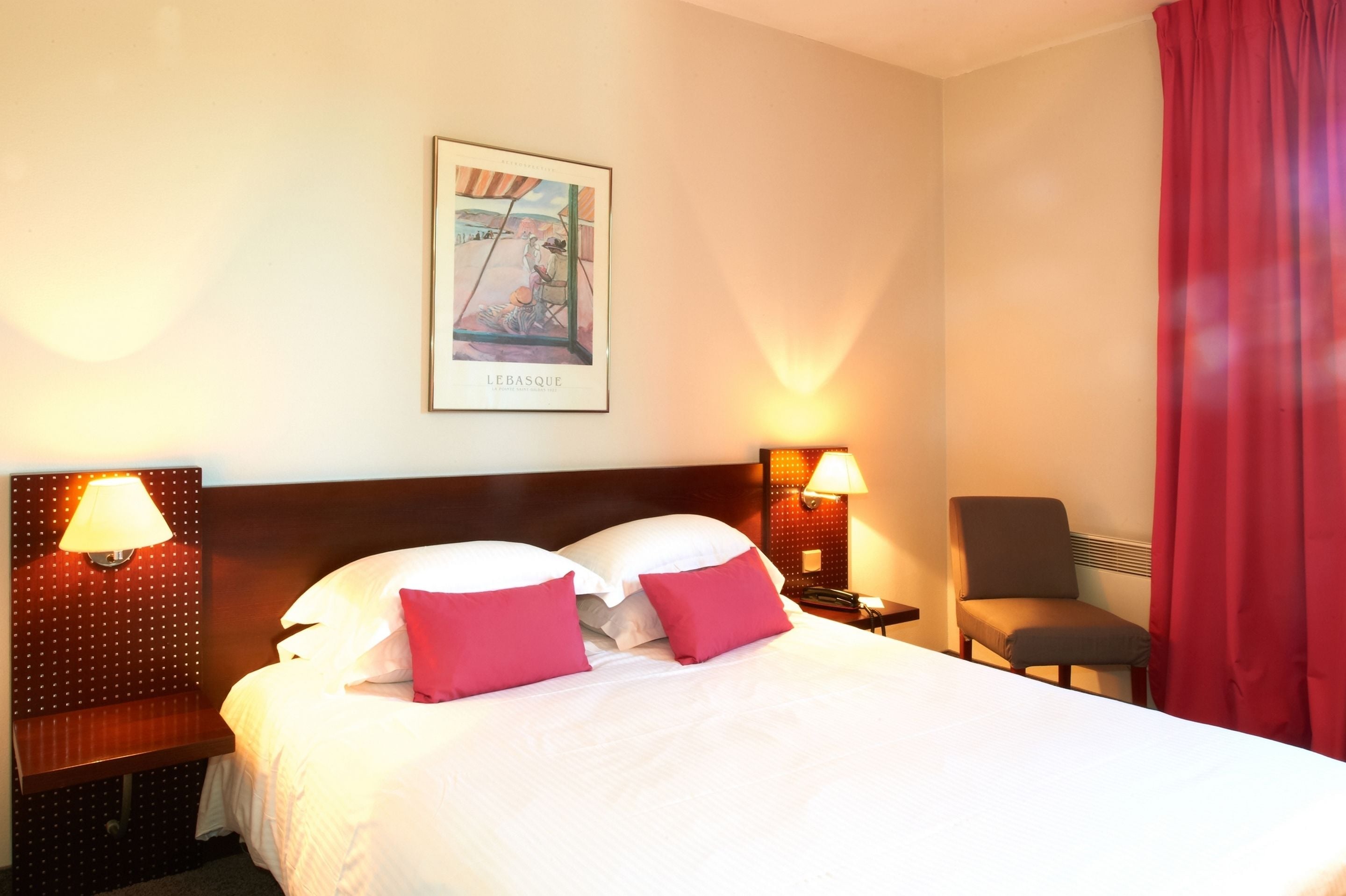 Una habitación de hotel con una cama grande, dos lámparas de noche, una silla y un cuadro en la pared.
