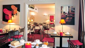 A hotel dining area with tables set for breakfast, featuring artwork on the walls and a sign reading "VITALITE".