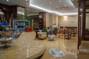 A hotel lobby with a marble reception desk, seating area, and a dining section. - La Noce (Chivasso)