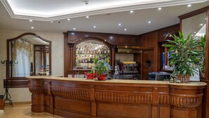A bar area with a wooden counter, a large mirror, and a variety of bottles.