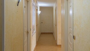 A hallway with doors on both sides, a tiled floor, and a light fixture on the ceiling.