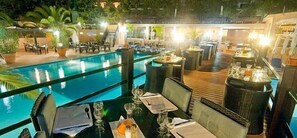 A rooftop bar with a pool, outdoor seating, and a view of the pool.