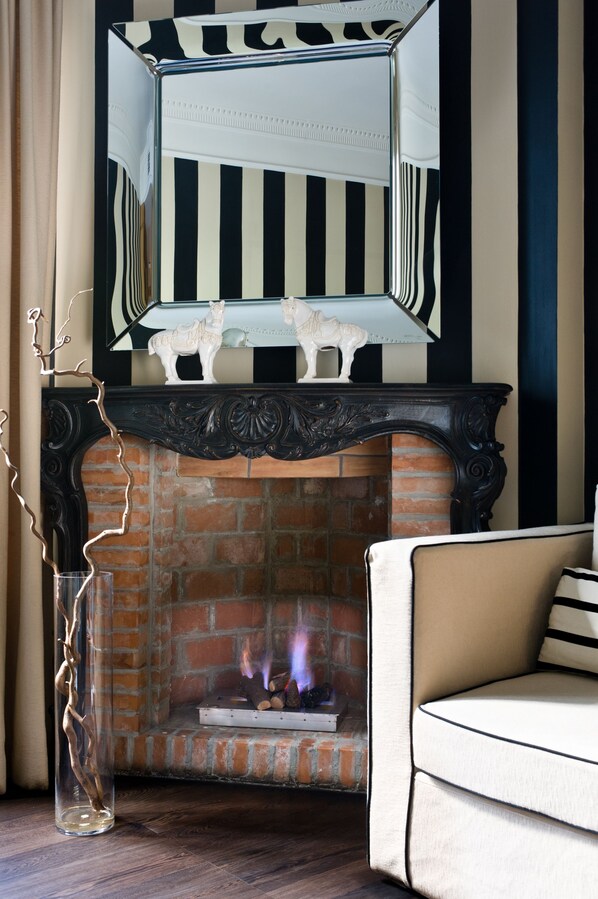 Una chimenea con diseño de ladrillo, un sofá blanco y un espejo decorativo encima.