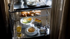 A breakfast trolley with croissants, a glass of orange juice, and a bowl of cereal on a balcony overlooking a historic town with buildings and a church. - Casa Montani (Rome)