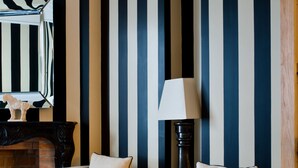 A room with striped wallpaper, two armchairs, a side table, a lamp, and a fireplace. - Casa Montani (Rome)