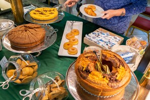 A buffet table with various baked goods, including a large cake, donuts, and pastries. - Hotel Sole (Montesilvano)