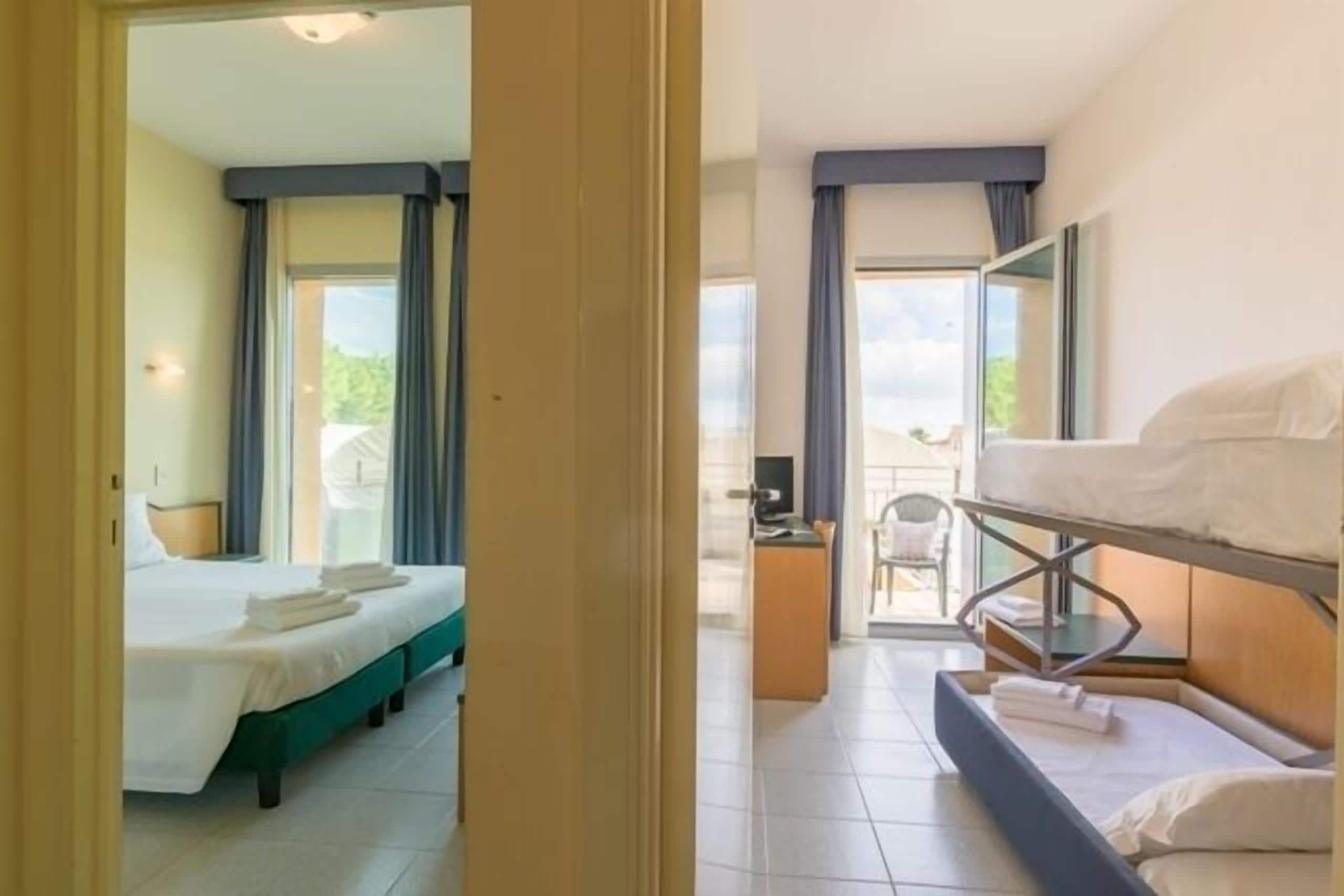 A hotel room with a bed, a desk, and a balcony.