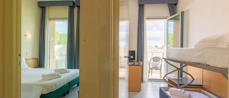 A hotel room with a bed, a desk, and a balcony.