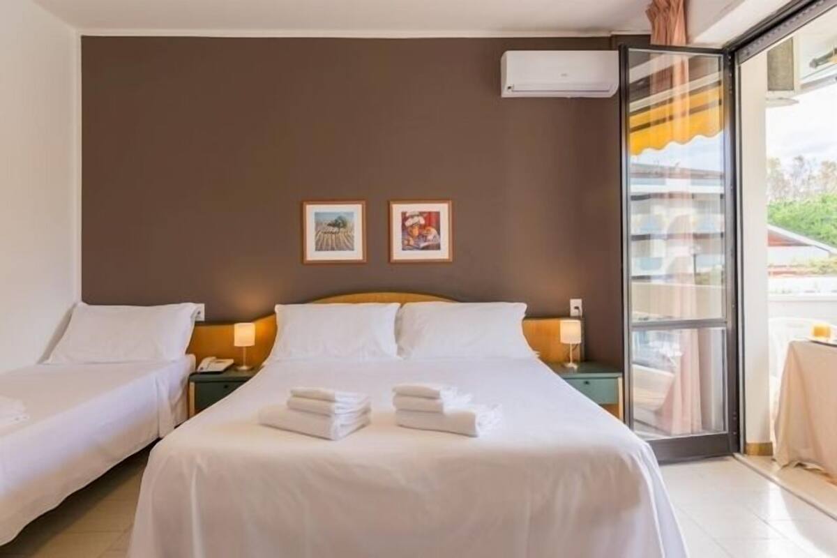 Ein Hotelzimmer mit zwei Betten, einem großen Fenster und zwei gerahmten Bildern an der Wand.