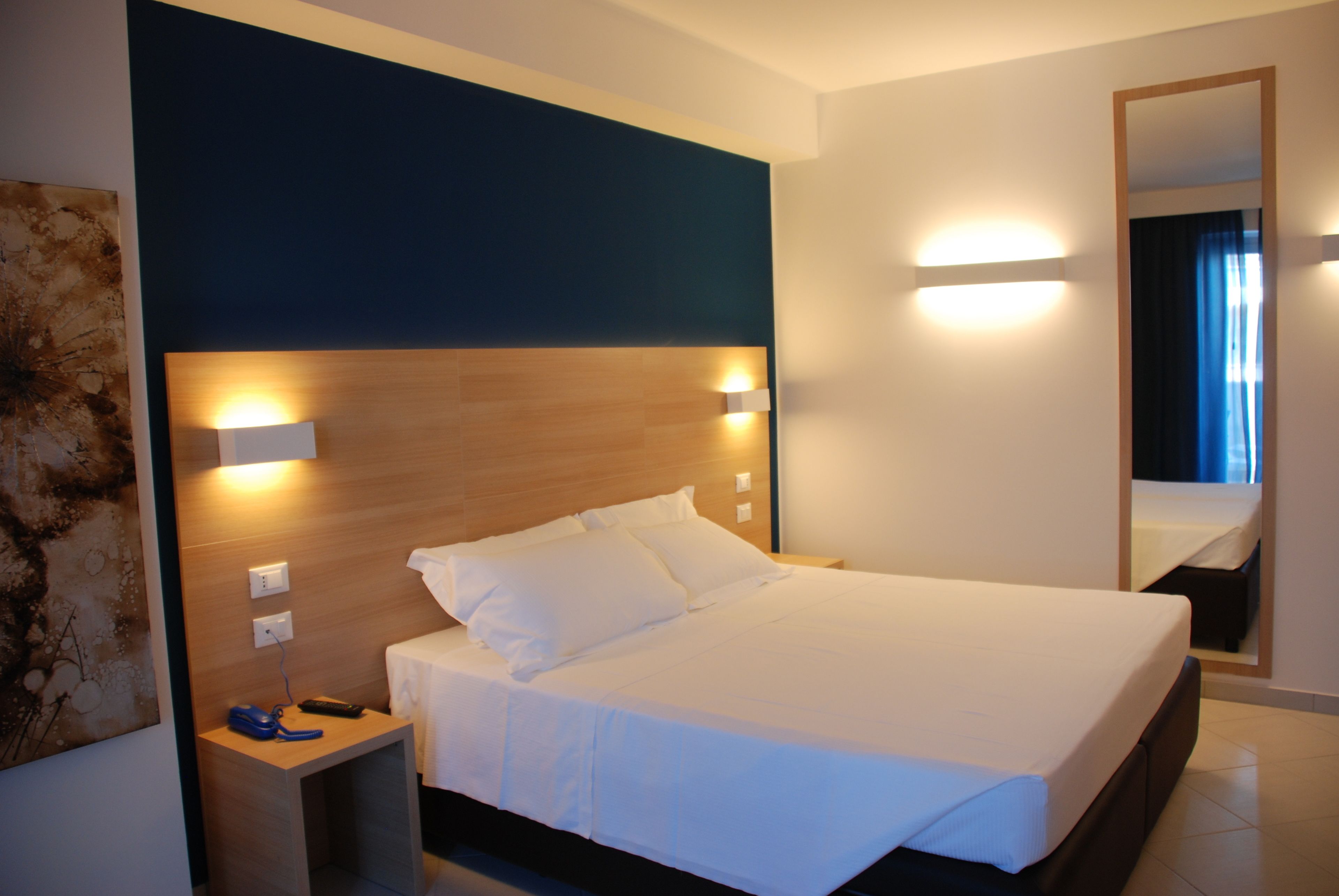 A neatly made bed with white linens in a modern hotel room.