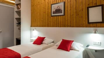 A hotel room with two beds, each with red and white bedding, and a wooden wall with a framed picture.