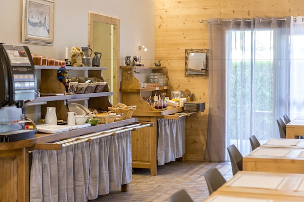 A cozy cafe with wooden interiors, a coffee machine, shelves with jars, and a window with curtains. - Fasthôtel Thônes (Thones)