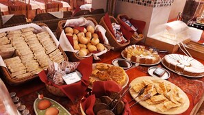 Buffet com diversos itens, incluindo pães, doces e sobremesas.
