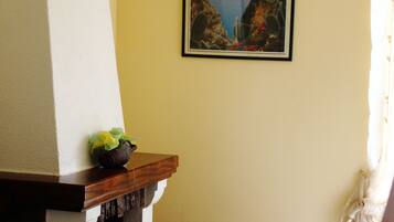 Cozy corner room with a fireplace, framed artwork, and a window with curtains.