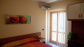 Camera da letto con un letto, un comodino, un condizionatore, un quadro di fiori e una porta scorrevole.