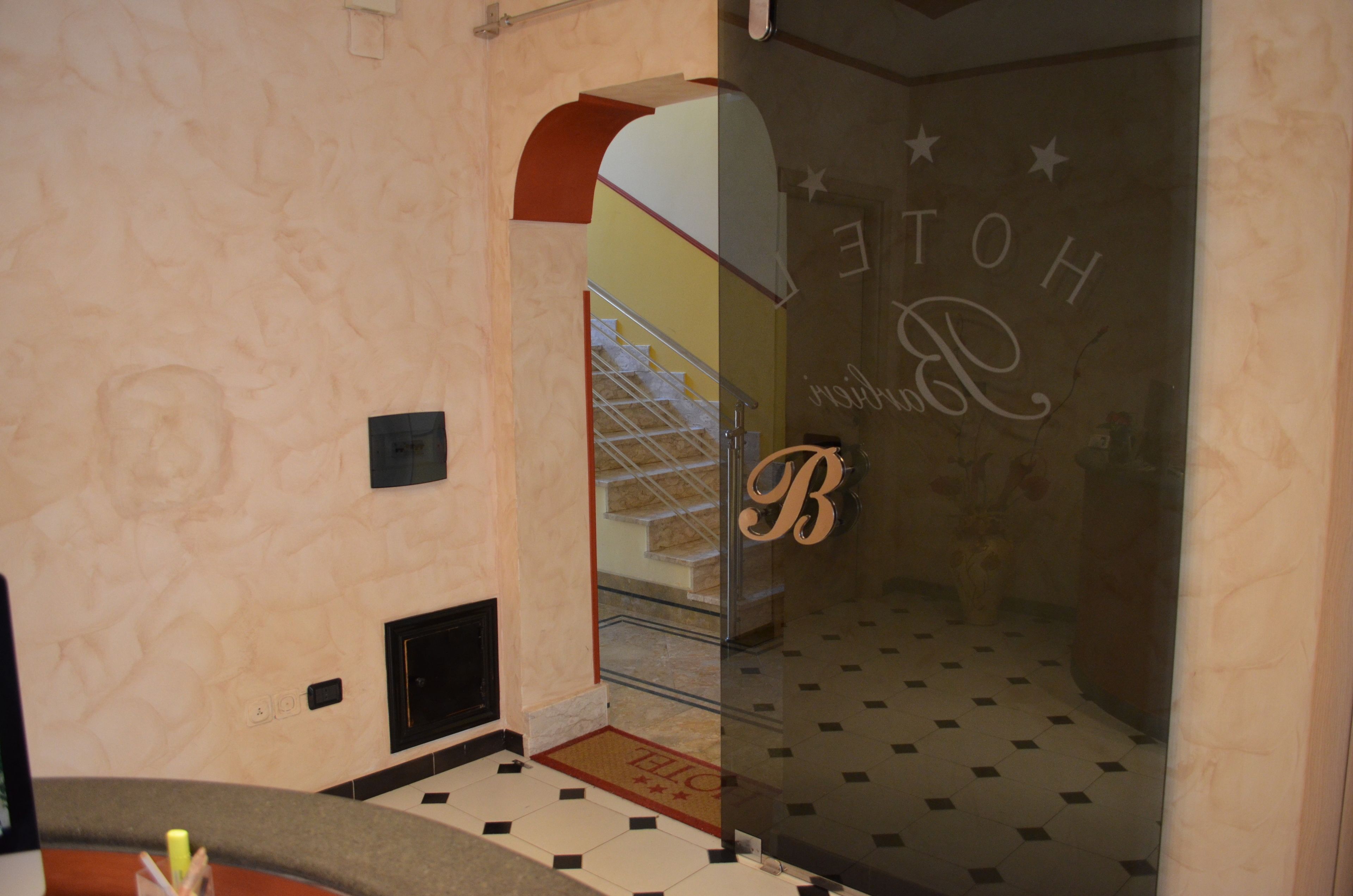 L’entrée d’un hôtel, avec une porte en verre, un escalier bien visible et un sol carrelé.
