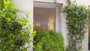 A building with a window covered by blinds, surrounded by lush greenery. - Albergo Al Moretto (Castelfranco Veneto)