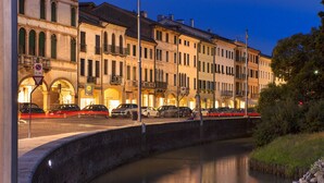 A canal with buildings on one side and a statue on the other. - Albergo Al Moretto (Castelfranco Veneto)