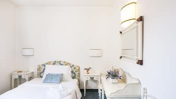 A hotel room with a bed, bedside tables, a dresser, a mirror, and wall-mounted lamps.